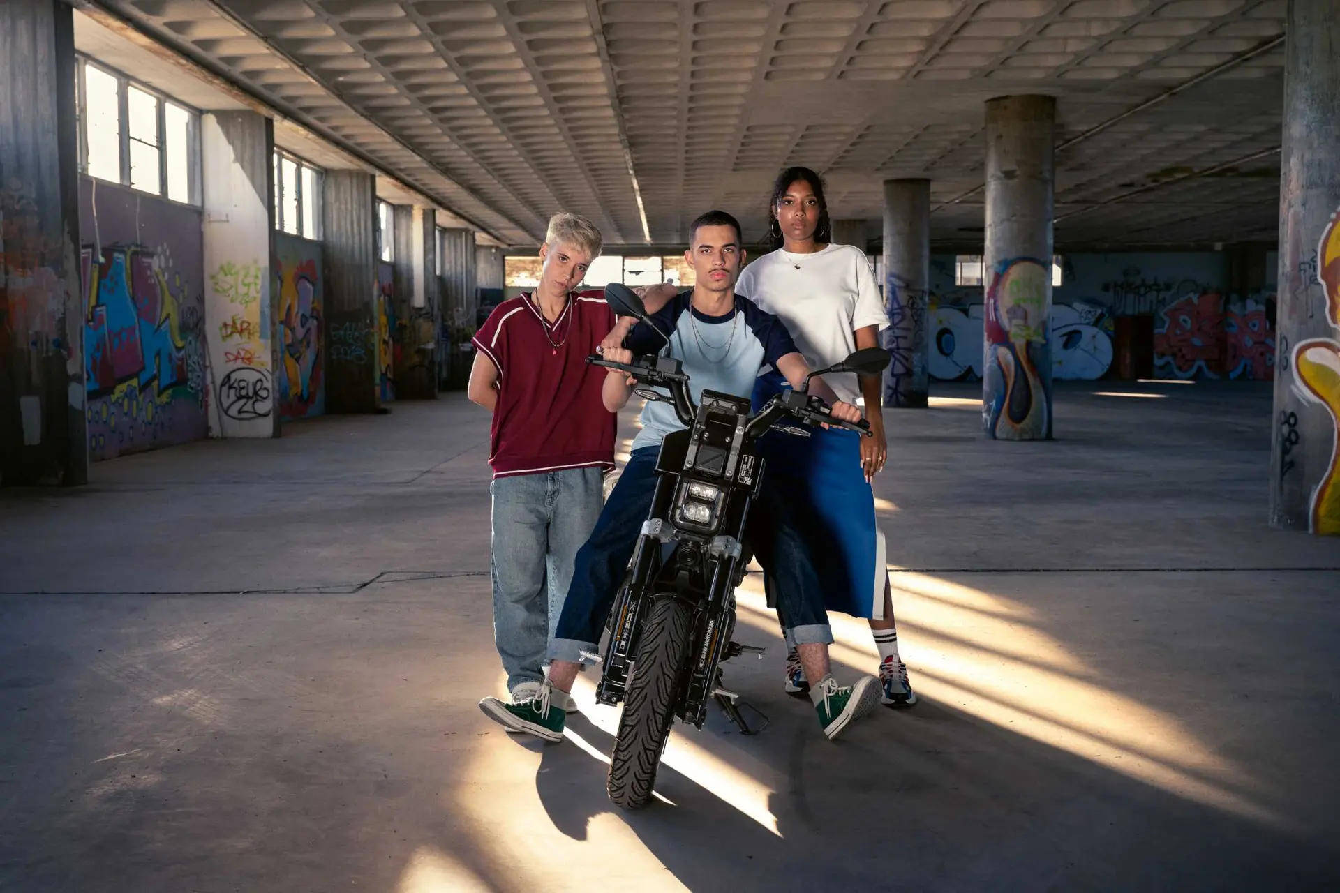 Front view of the BMW CE 02 with three people in an urban building