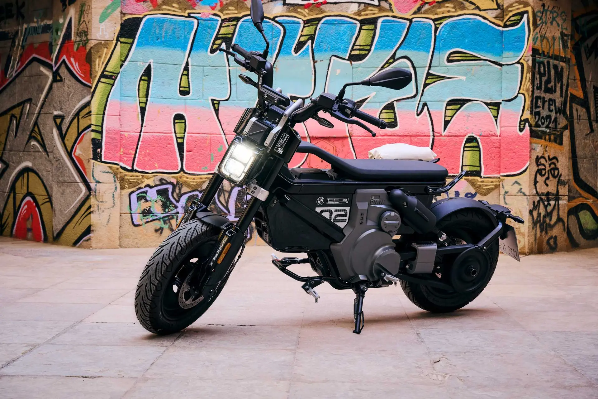 BMW CE 02 electric motorcycle in front of a colourful urban wall