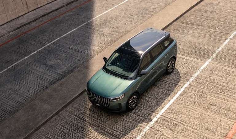 Green JAECOO J5 driving on an urban road