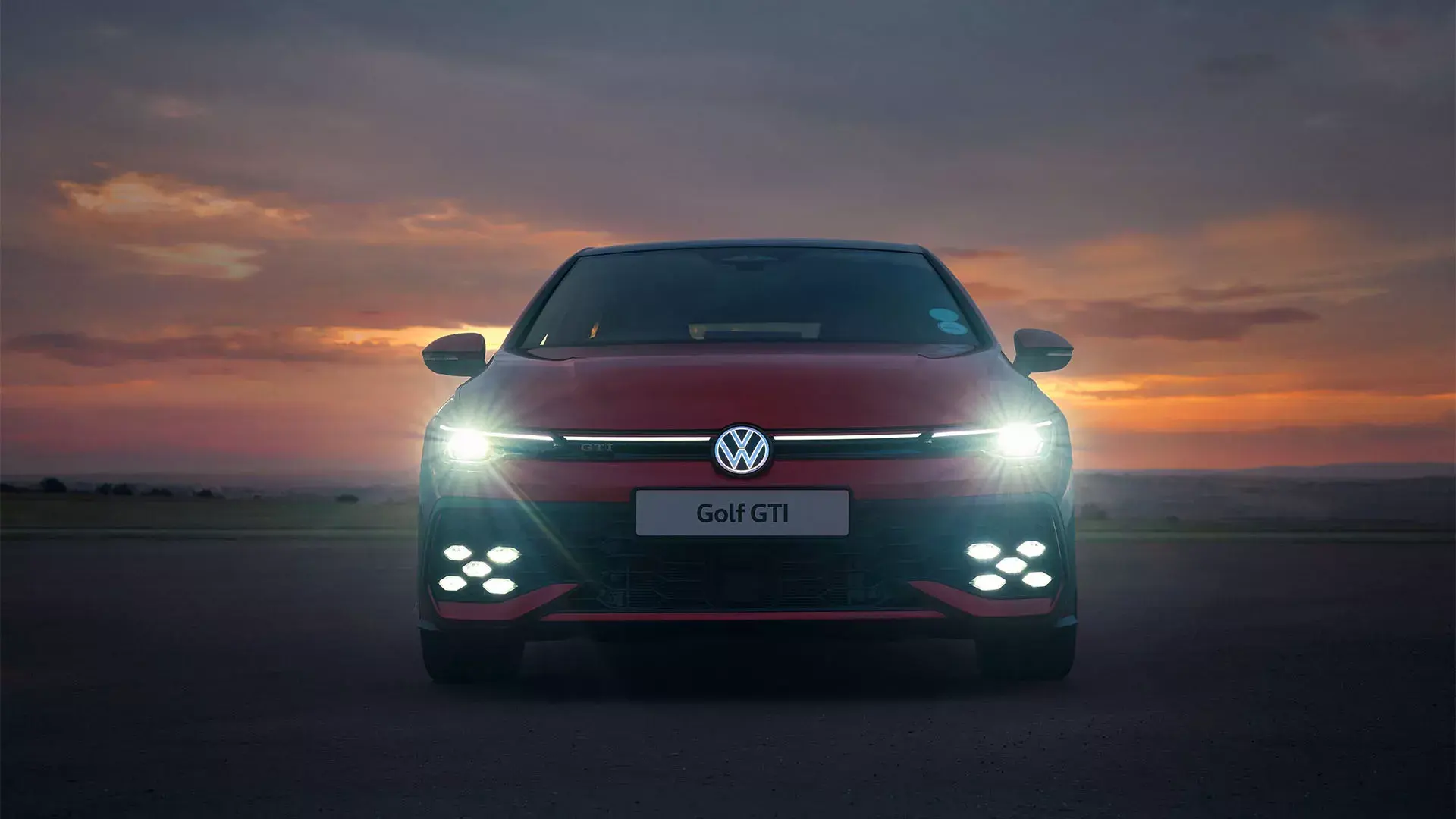 Red Volkswagen Golf GTI photographed from the front at sunset